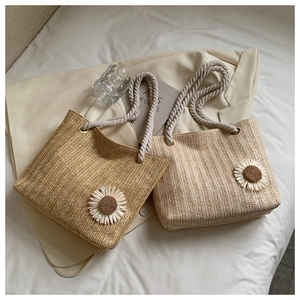 Detail of woven straw tote bags with white daisy embroidery and thick cotton rope handles