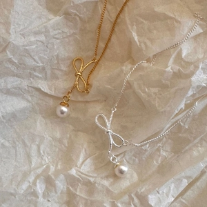 Detail view of gold and silver bow pearl necklaces on artistic vintage textured paper