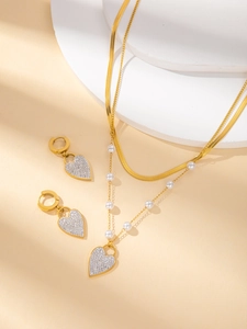 Detail einer doppelreihigen Goldkette mit Herzanhänger und passenden Ohrsteckern