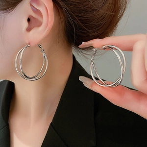 Fashionable twisted geometric silver hoop earrings shown on model in a stylish studio shot