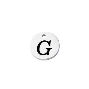 Macro shot of silver stainless steel round tag featuring engraved uppercase letter G