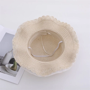 Detailed interior of a beige straw sun hat with white lace trim and elastic chin strap