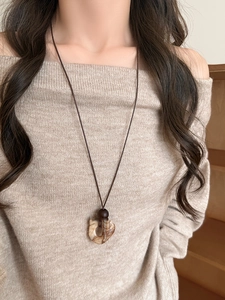 Close-up of irregular wood resin pendant with natural marble texture on brown cord