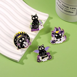 Set of four black magic cat enamel pins with wizard hats and crystal balls on a green surface