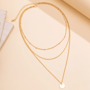 Macro view of tiered gold-tone chain necklaces with a round metal pendant detail