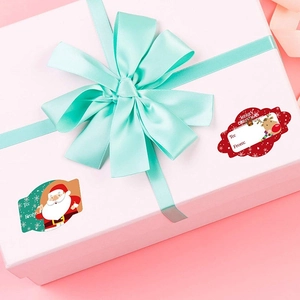 Close-up of Merry Christmas gift tags featuring Santa and reindeer on a wrapped gift box