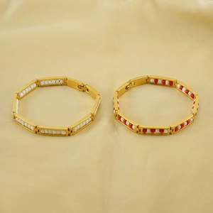 Detail of gold-plated beaded bracelets with white and red accents on beige fabric