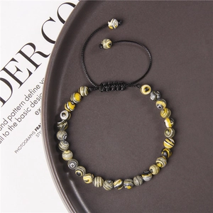 Nahaufnahme der 6mm Natursteinperlen mit gelben Spiralmustern am geflochtenen Armband