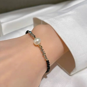 Detail of beaded bracelet with faceted grey crystals and a round white pearl on wrist