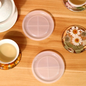 Top view of translucent round silicone mold with dried flower resin coaster on wooden desk