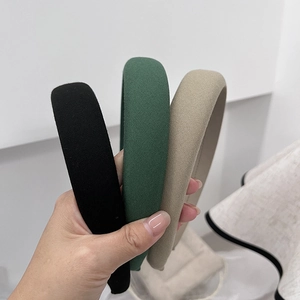 Three minimalist sponge headbands in black, green, and beige fabric held by hand