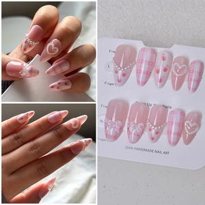 Detailed view of handmade pink plaid almond nails with 3D pearls and heart accents