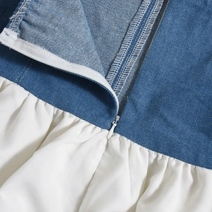 Détail du tissu denim bleu et blanc avec couture contrastée et fermeture éclair invisible