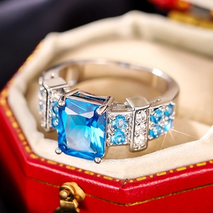 Close-up of emerald cut blue gemstone ring with micro-pave setting in red gift box