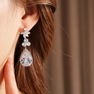 Macro detail of teardrop zircon pendant earring with floral setting and silver finish