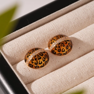 Macro view of leopard print dome earrings with diamond metal band in jewelry box