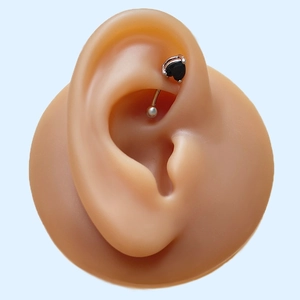 Macro shot of black heart zircon curved barbell piercing on a silicone ear model