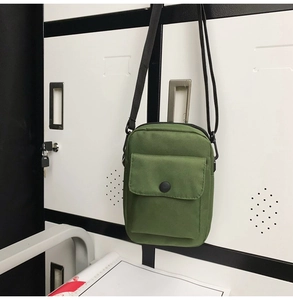 Detail view of military green canvas crossbody bag with snap pocket on storage locker