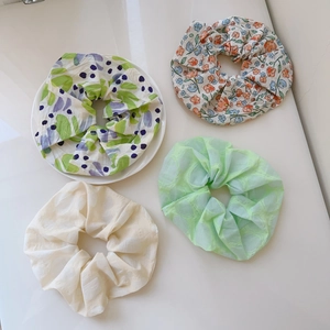 Close-up of four floral print scrunchies in chiffon fabric showing natural pleats and textures