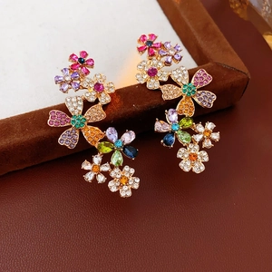 Nahaufnahme bunter Strass-Blumenohrringe mit hochwertiger Vergoldung auf braunem Leder