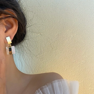 Boucles d'oreilles carrées dorées à texture marbre portées par un mannequin de profil