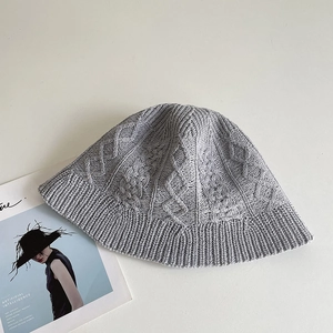 Macro detail of grey knit bucket hat showing premium braided cable patterns and texture