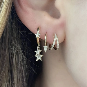Macro shot of gold star hoop earrings and triangular dangles with zircon pavé setting