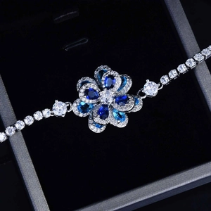 Detailed shot of a silver floral tennis bracelet with blue and clear zircon crystals