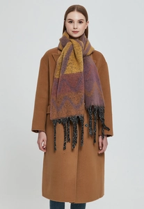 Close-up of color-block knit scarf with wave patterns and thick black tassels detail