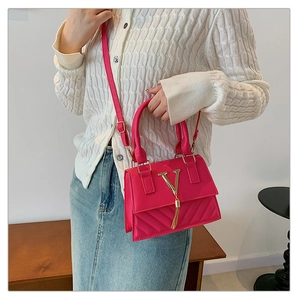 Detailed shot of bright pink PU leather bag with gold V-hardware and metal tassels