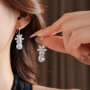 Close-up of silver flower and waterdrop earrings with zircon insets on model