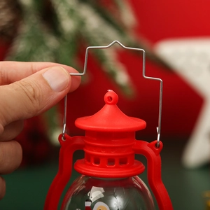 Close-up of red Christmas mini lantern with Santa pattern and silver metal hook