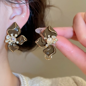 Close-up of brown flower earrings with gold edges and crystal center on model