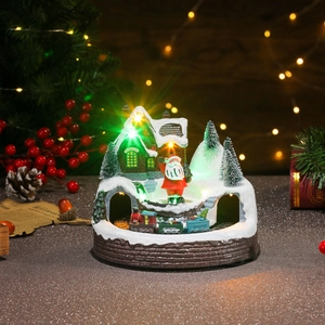 Detailed Christmas village scene with colorful LED lights and rotating train on snowy cabin