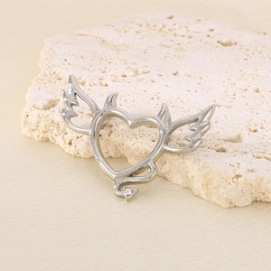 Macro shot of silver heart pendant with devil wings and crystal on stone base