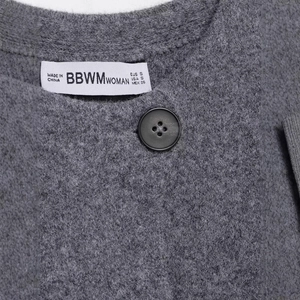 Gilet en maille grise avec bouton noir minimaliste et étiquette de marque tissée