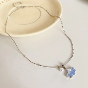 Close-up of ginkgo leaf pendant with blue gradient crystals and a white pearl accent