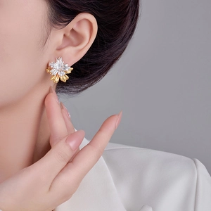 Close-up of a model wearing stylish two-tone floral earrings in gold and silver finish