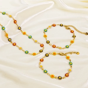 Golden stainless steel daisy jewelry set with colorful enamel flowers on satin fabric