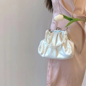 Close-up of white pleated cloud bag with vintage metal clasp and chain strap