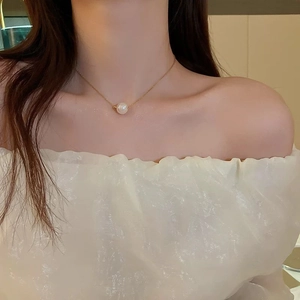 Close-up of a minimalist gold stainless steel necklace with a single white pearl on a model