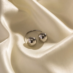 Polished silver stainless steel open ring with two large spheres on silk fabric