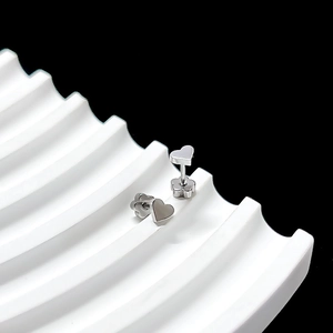 Detail of silver heart stud earrings with petal screw backs on a wavy white tray