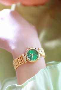 Close-up of elegant gold women watch with green dial and diamond markers on wrist
