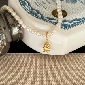 925 silver pearl necklace with 3D golden bear pendant on vintage background