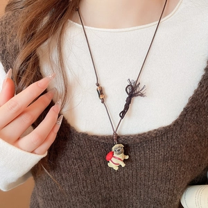 Detail of a handmade pug puppy pendant on a brown cord necklace with wooden beads