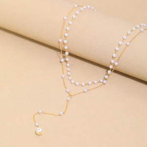 Detail of elegant gold-tone Y-shaped double layer necklace with polished white pearls