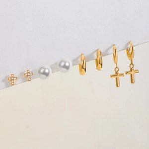 Set dettagliato di quattro orecchini dorati con croci, perle bianche e cristalli brillanti