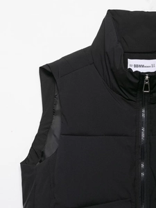 Detail of black quilted vest featuring stand collar, metal zipper, and brand size label