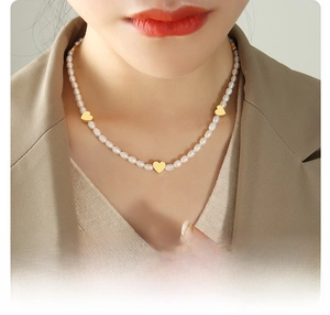 Detail of baroque freshwater pearl necklace with 18k gold plated heart pendants on model